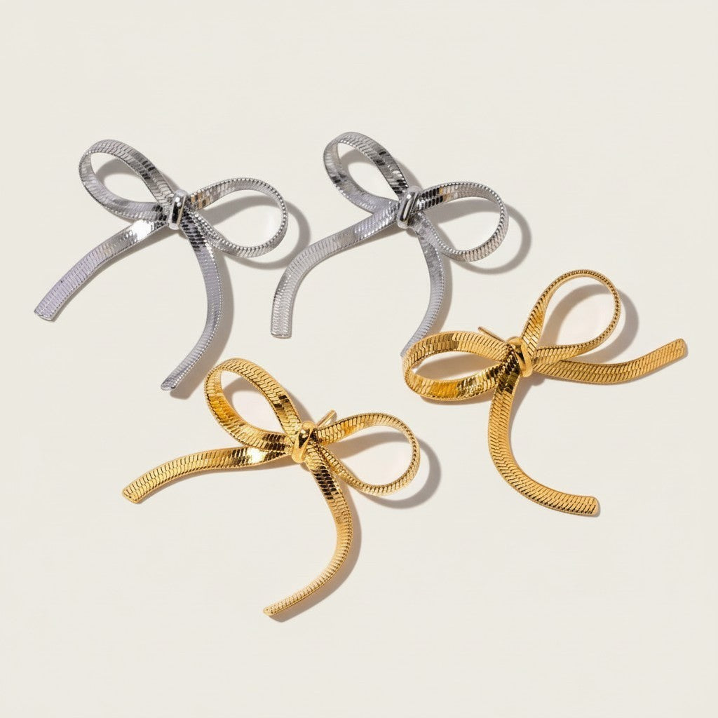 Seraphina Treasures Alathea earrings in gold and silver, featuring a flat snake chain in a delicate bow design.