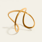 Seraphina Treasures Alcyone gold-tone metal cuff bracelet with an abstract, intertwined design.