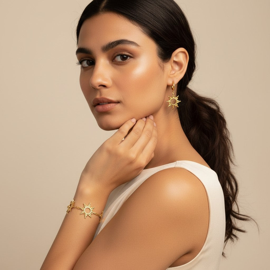 Seraphina Treasures Anthea gold-tone bracelet and hoop earrings set with sunburst designs. Model wears the jewelry with a cream dress.