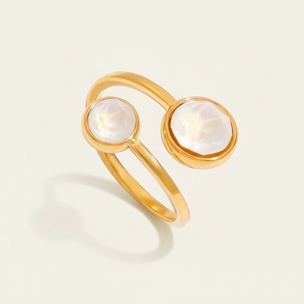 Seraphina Treasures Calyra ring with two round, iridescent white stones set in gold-tone metal. Modern geometric design.