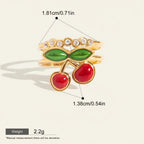Seraphina Treasures Myrrine gold ring with red cherry charms and green leaves, accented with clear zirconia stones.