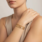 Seraphina Treasures Chrysara gold bracelets stacked on a woman's wrist. Features heart and chain links.