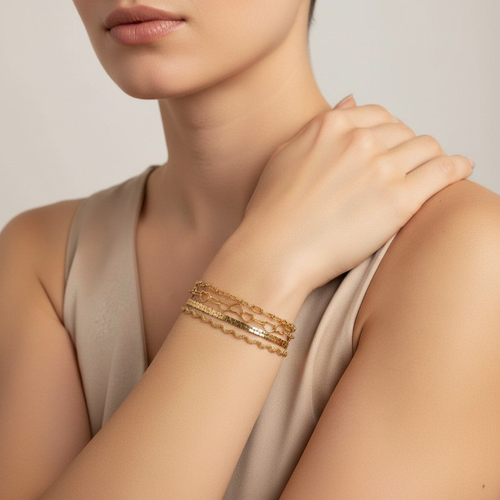 Seraphina Treasures Chrysara gold bracelets stacked on a woman's wrist. Features heart and chain links.
