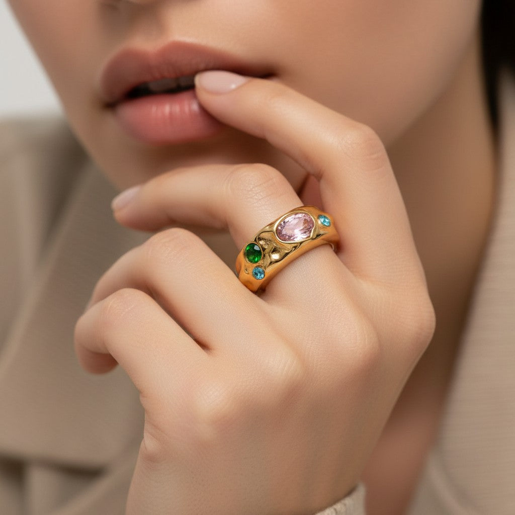 Seraphina Treasures Corvian ring with a gold band, featuring a large pink gemstone and smaller green and blue gemstones.