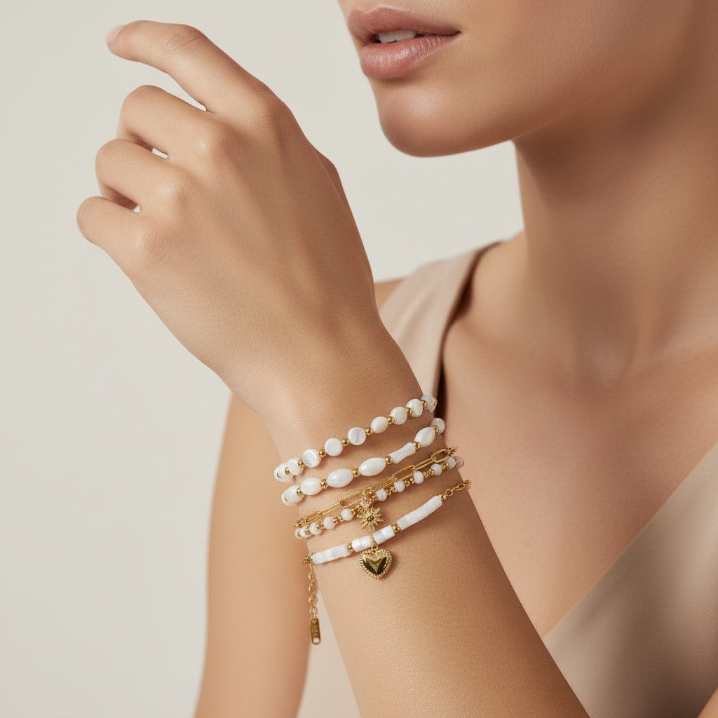 Seraphina Treasures Delia bracelet set featuring four gold-tone chains with white shell beads and gold accents. Includes heart and sun charms.