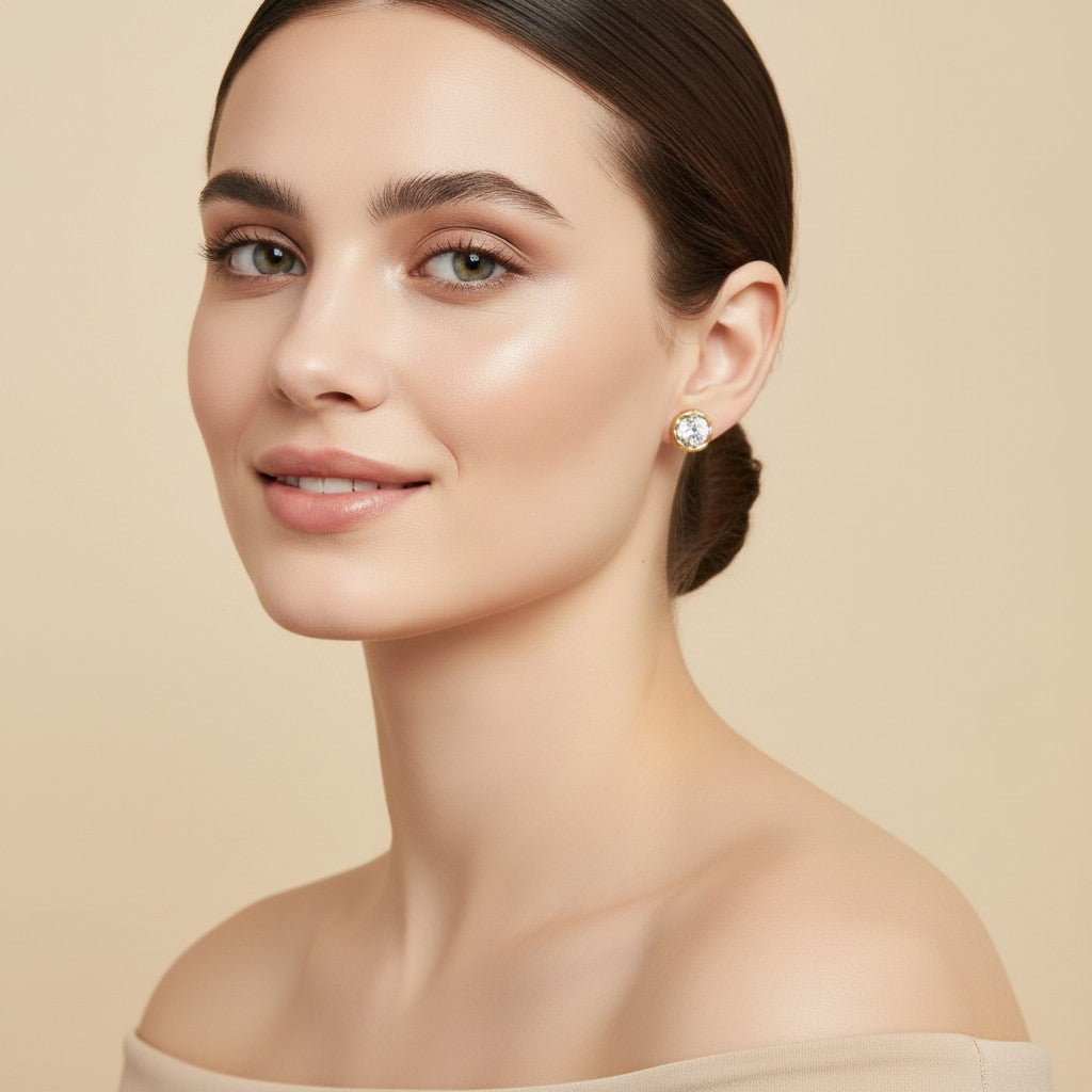 Seraphina Treasures Diamora gold stud earrings with clear crystal center, detailed bezel, worn by a model.