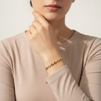 Seraphina Treasures Elpis gold bracelet with colorful flower-shaped charms and pearl accents on a woman's wrist.
