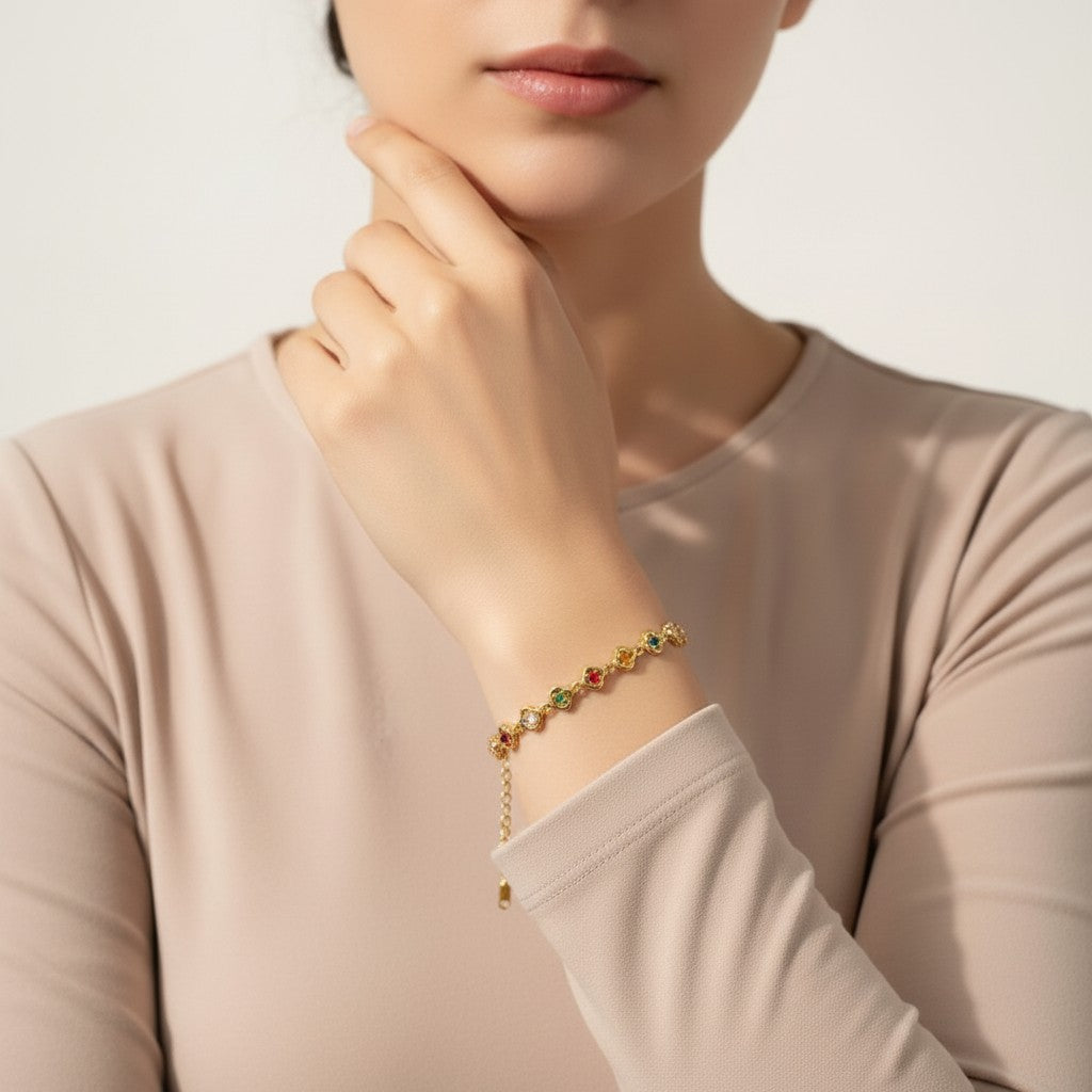 Seraphina Treasures Elpis gold bracelet with colorful flower-shaped charms and pearl accents on a woman's wrist.