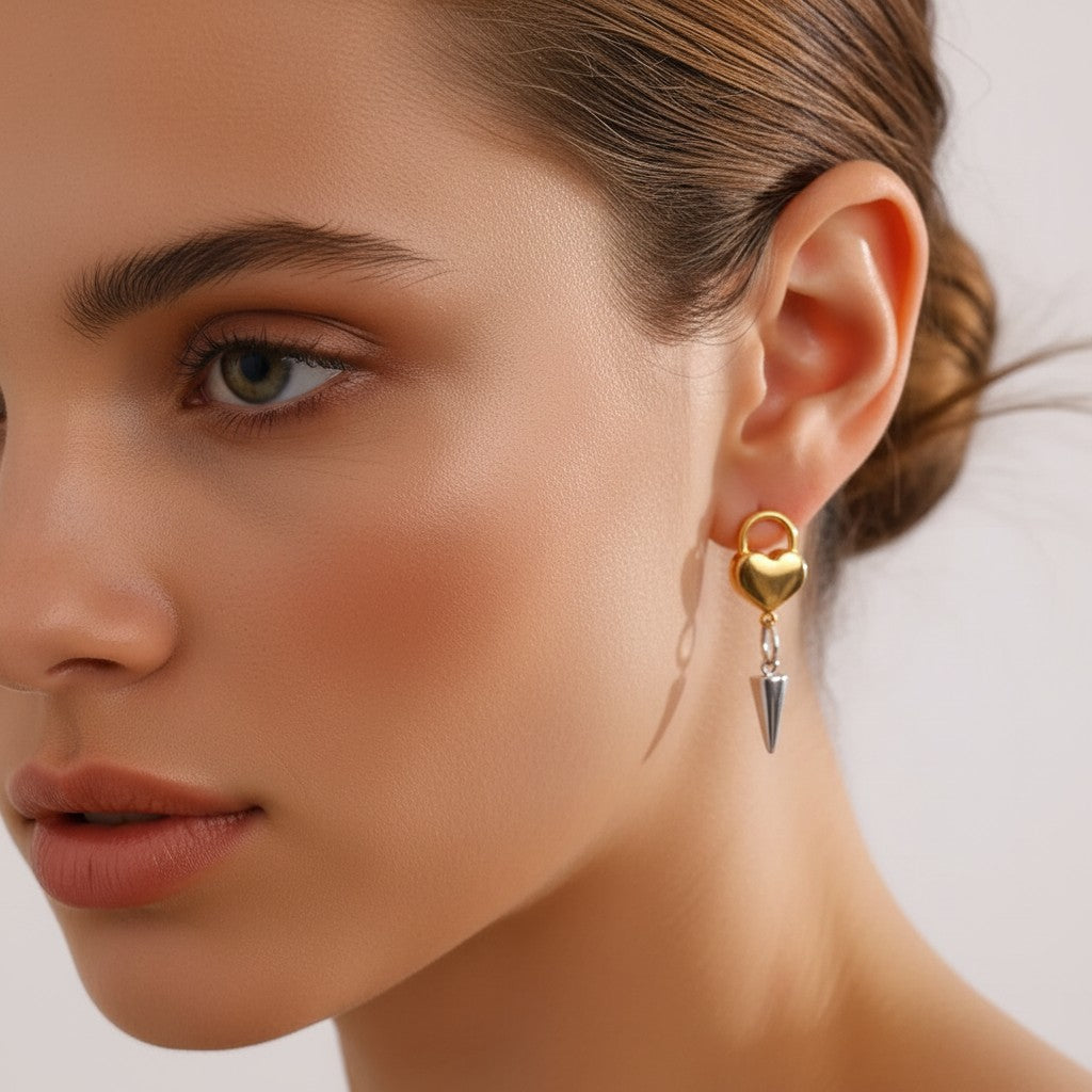 Seraphina Treasures Glyria earrings: gold heart lock with silver cone pendant. Edgy, playful statement jewelry.