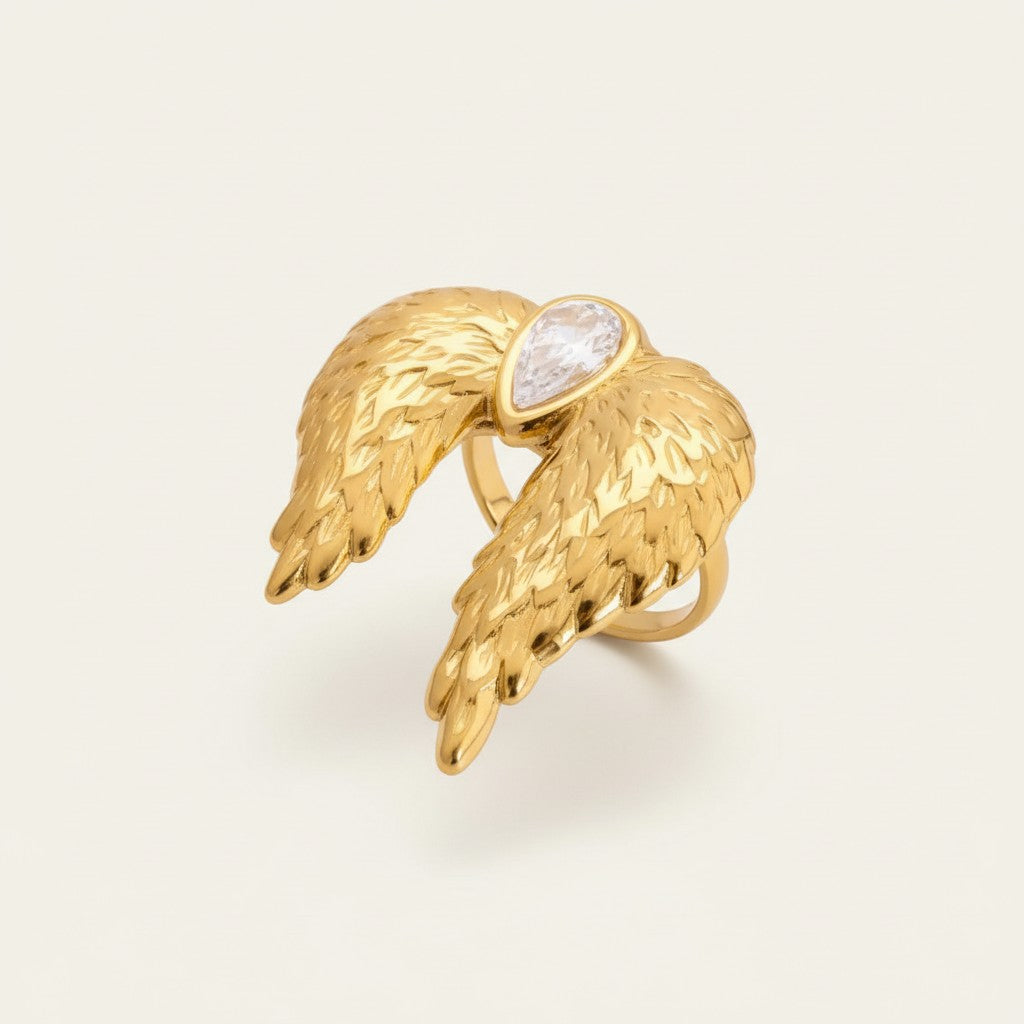 Seraphina Treasures gold adjustable ring with large textured angel wings and a pear-shaped clear crystal.