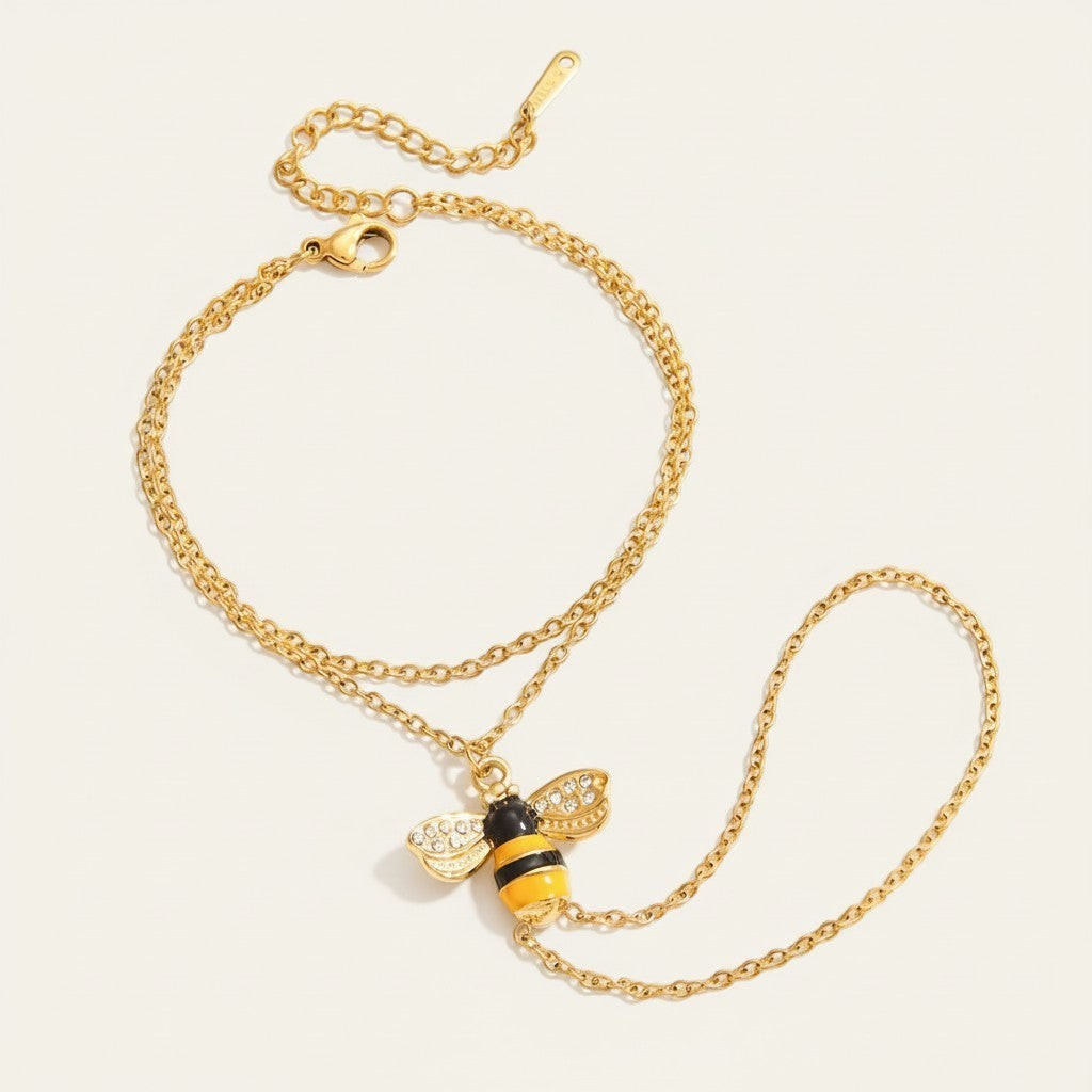 Seraphina Treasures gold-tone bracelet connected to a finger ring with a bee charm adorned with zircon accents.