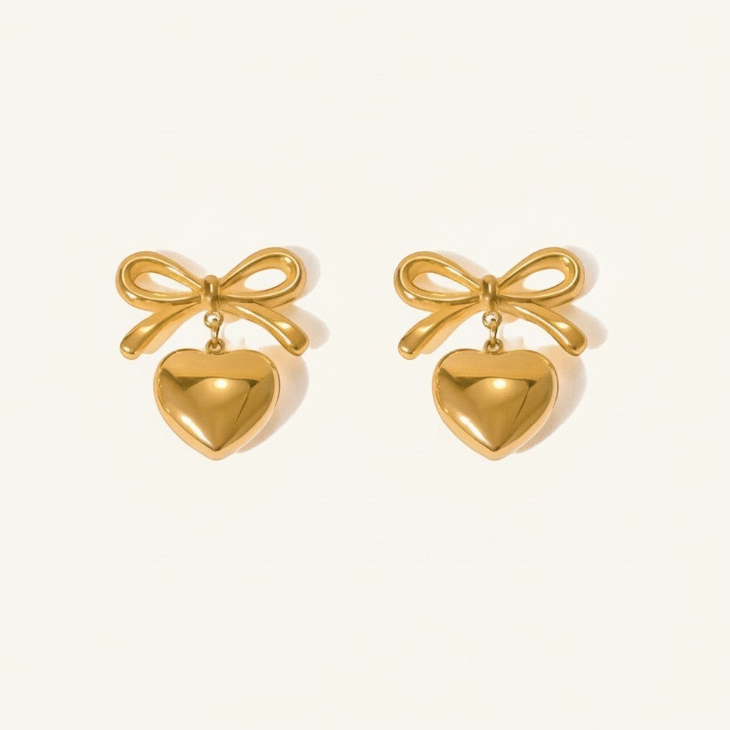 Seraphina Treasures gold-tone metal bow earrings with dangling heart pendants.