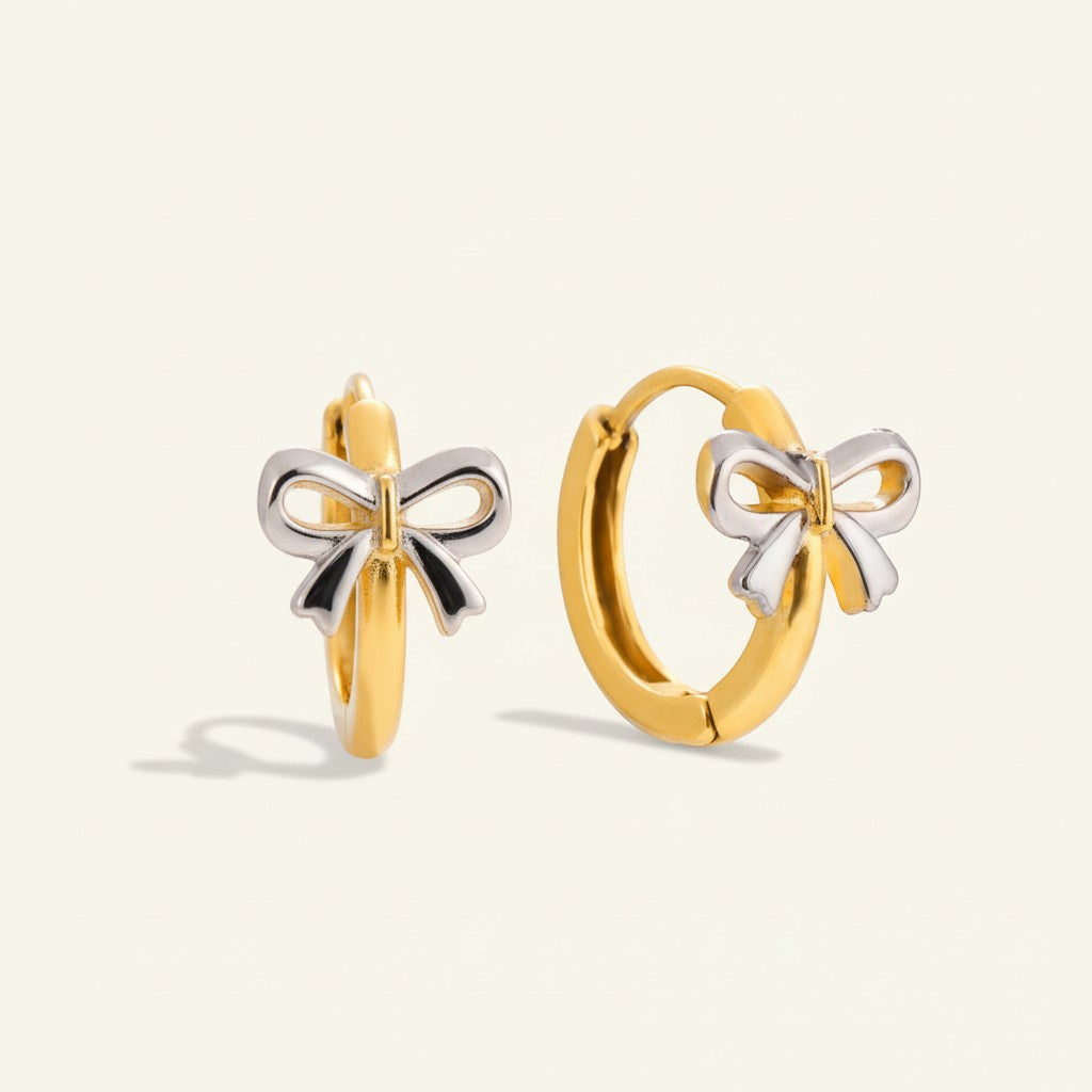 Seraphina Treasures gold hoop earrings with a two-tone silver and gold bow charm. Perfect for adding a playful touch.