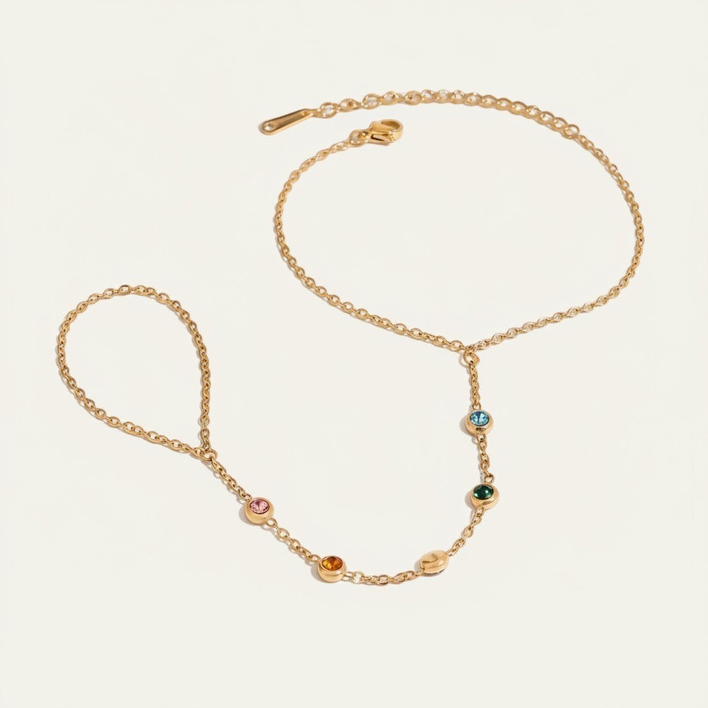 Seraphina Treasures gold chain bracelet with colorful zircon accents, connecting to a finger loop.