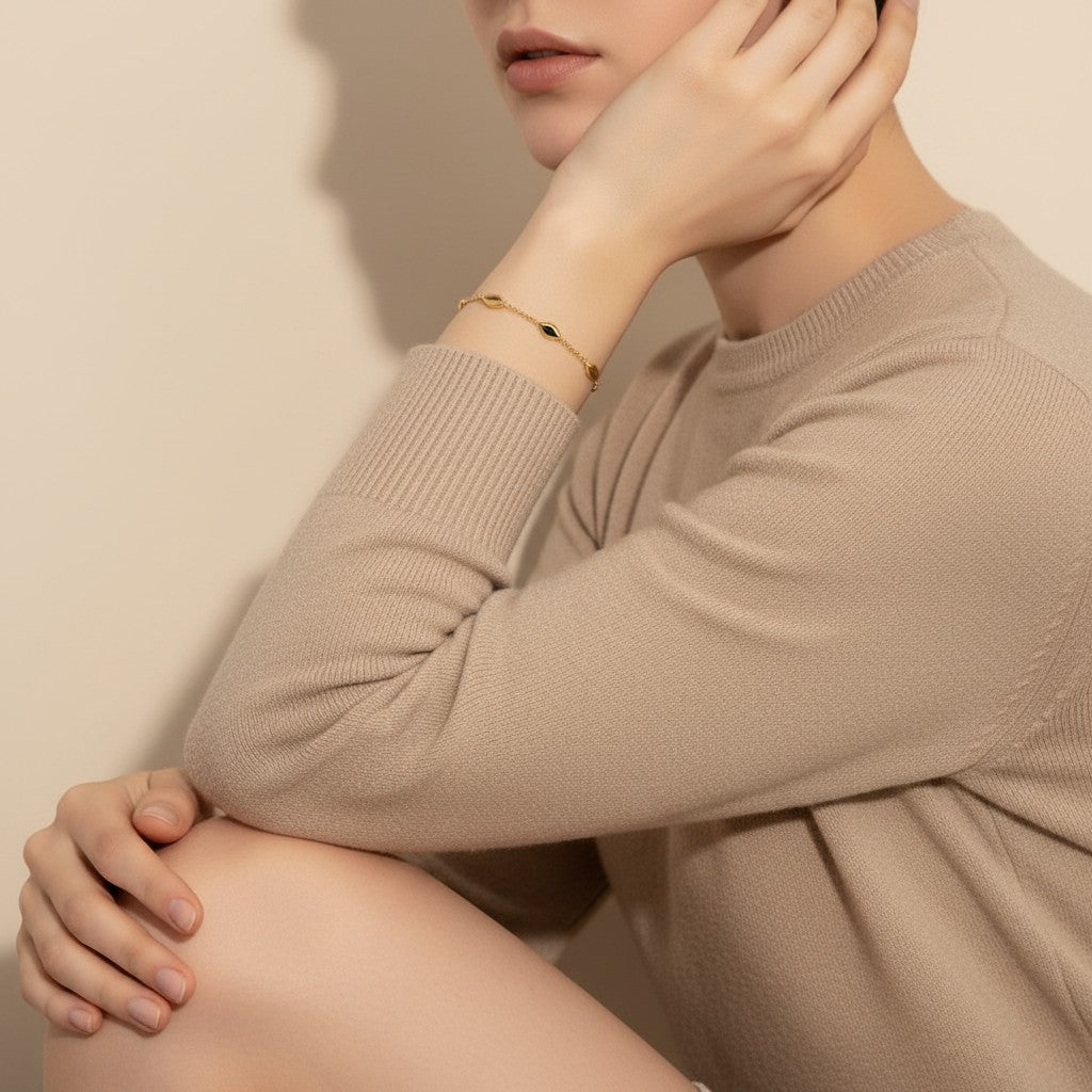 Seraphina Treasures Niobe gold bracelet with oval links on a woman's wrist, paired with a beige sweater.