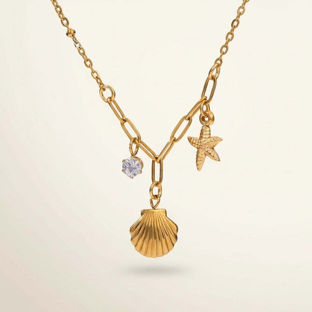 Seraphina Treasures gold necklace with shell, starfish, and zircon charms. Delicate chain with mixed links.