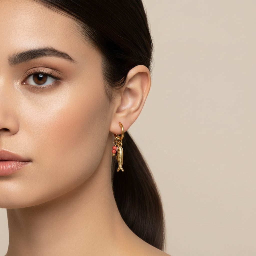 Seraphina Treasures gold hoop earring with a dangling fish charm and red beads.