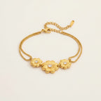 Seraphina Treasures gold-tone bracelet with three floral charms, each featuring a cubic zirconia center. Delicate double chains.
