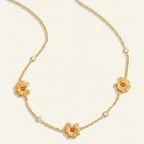 Seraphina Treasures gold necklace with three floral charms featuring orange centers and clear crystal accents.