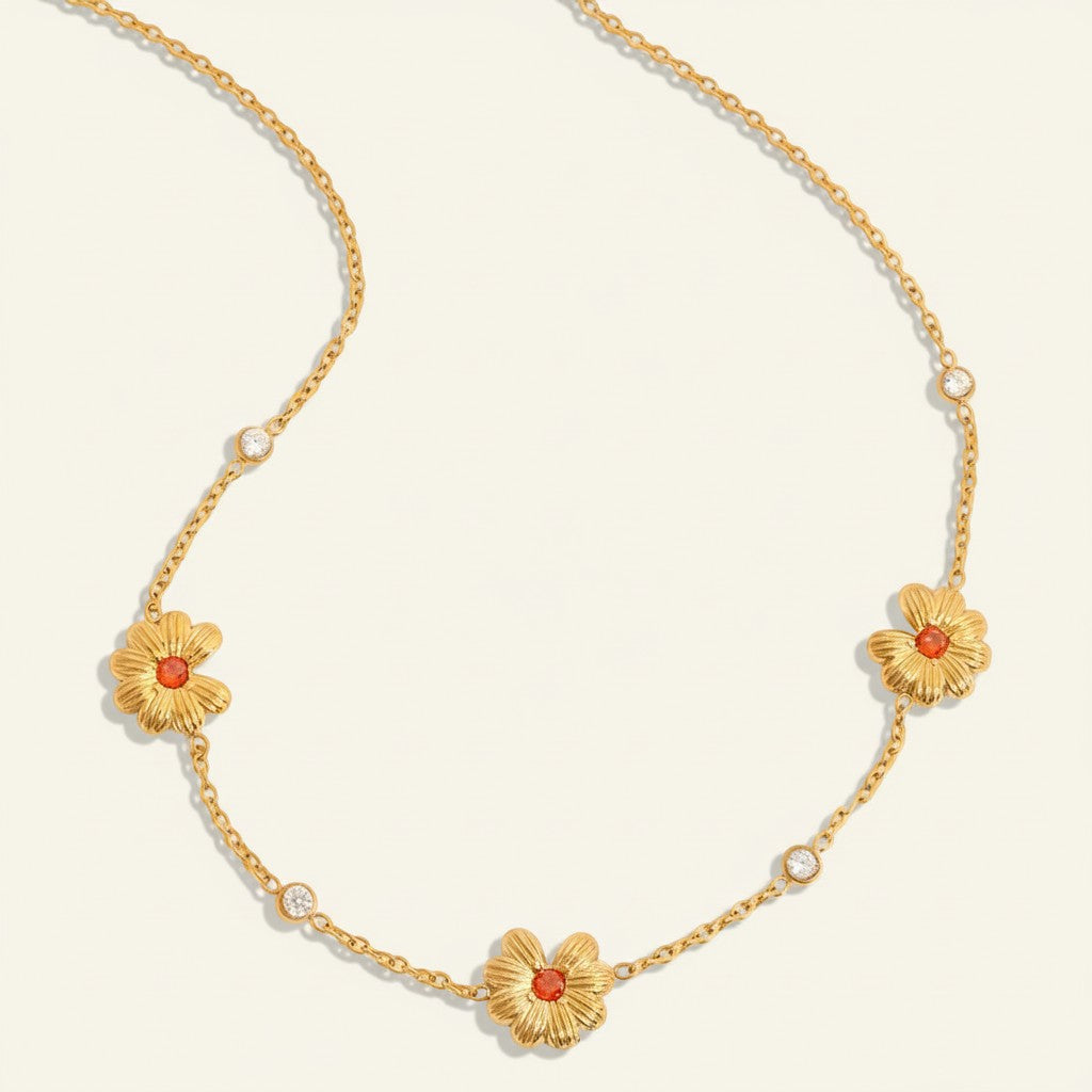 Seraphina Treasures gold necklace with three floral charms featuring orange centers and clear crystal accents.