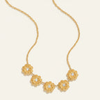 Seraphina Treasures gold necklace with five textured floral pendants, each with a clear crystal center.