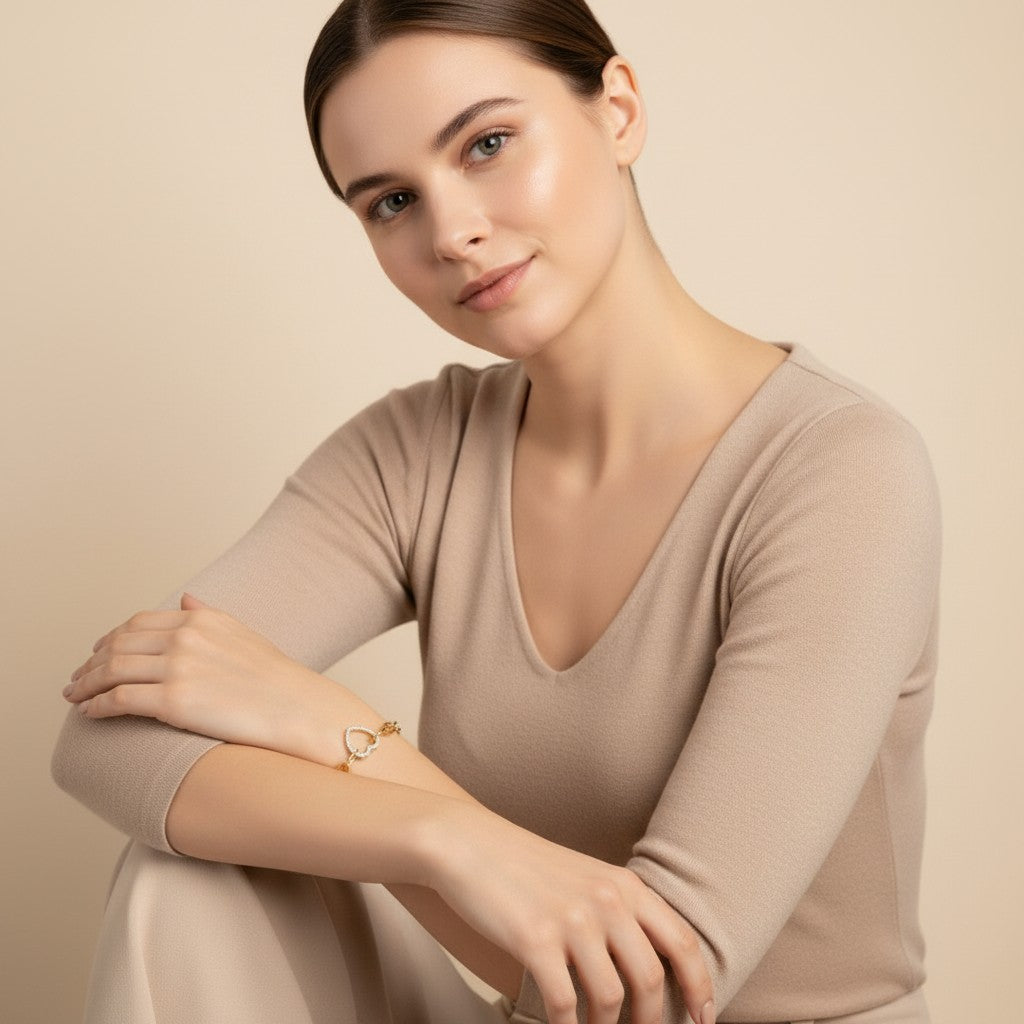 Seraphina Treasures gold chain bracelet with a crystal-encrusted heart pendant on a woman's wrist.