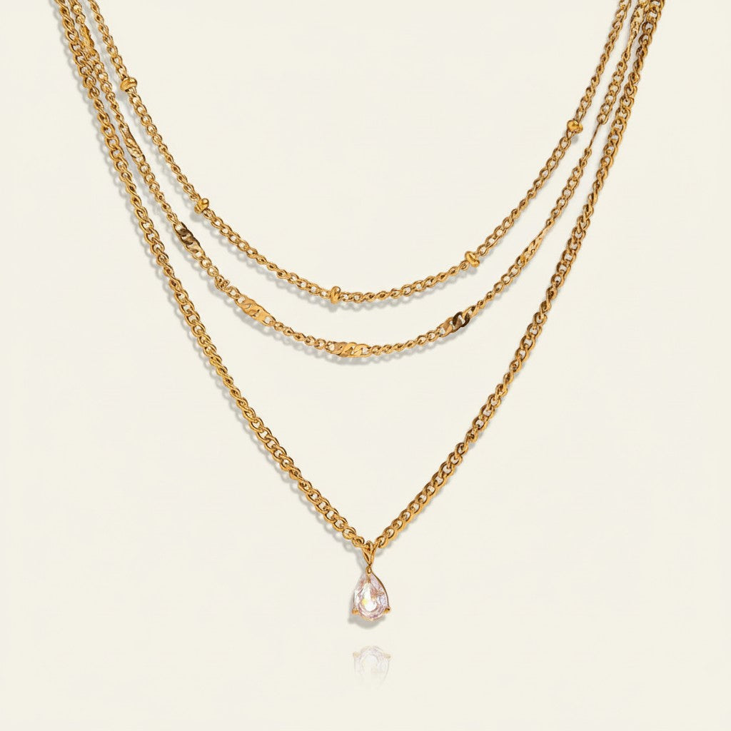 Seraphina Treasures gold layered necklace with a pear-cut white zircon pendant. Delicate chains with bead and flat link accents.