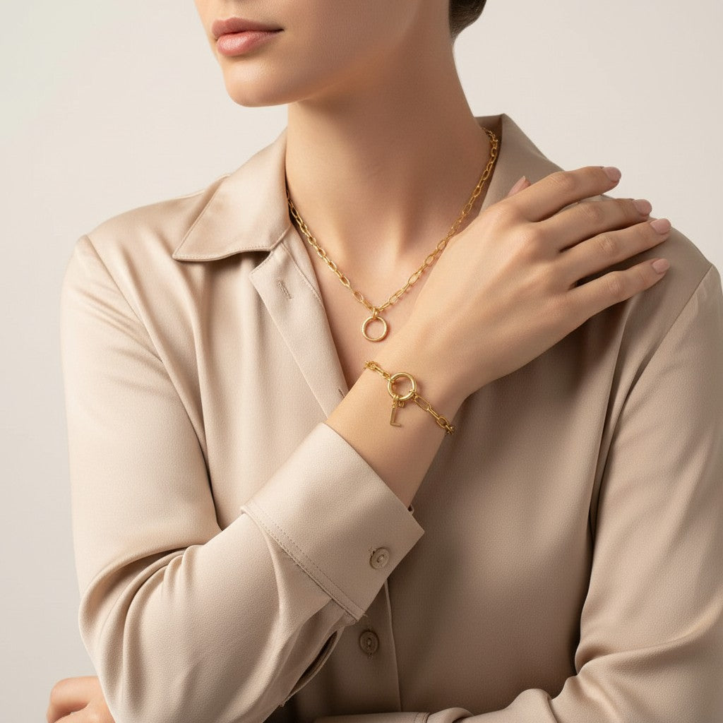 Seraphina Treasures gold chain bracelet with a circular clasp and a dangling letter L charm, worn on a woman's wrist.