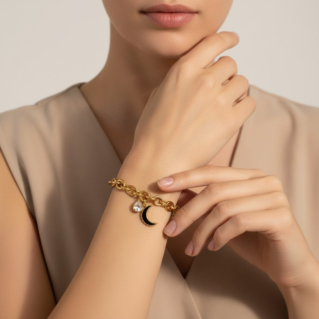 Seraphina Treasures gold chain bracelet with a clear zirconia water drop charm and a black crescent moon charm.