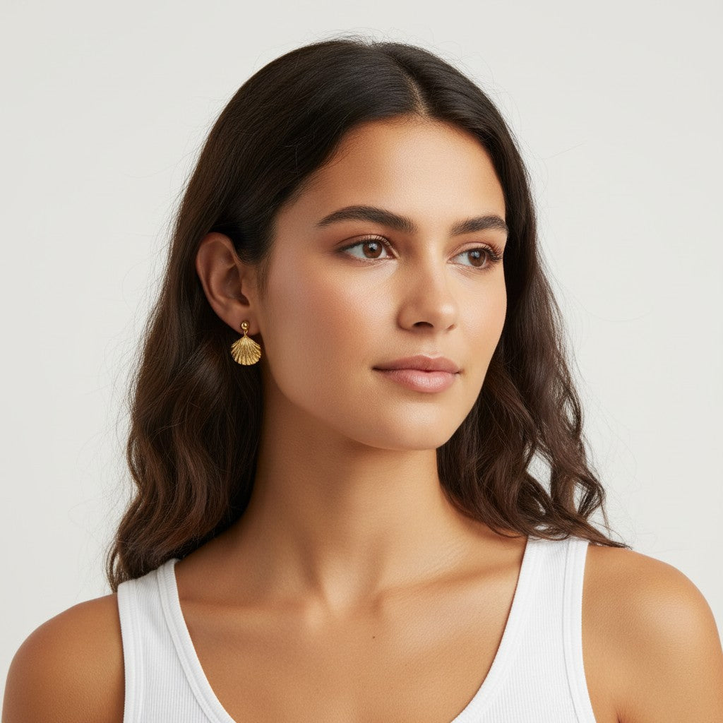 Seraphina Treasures gold seashell drop earrings worn by a woman with blonde hair, featuring a delicate shell pendant.