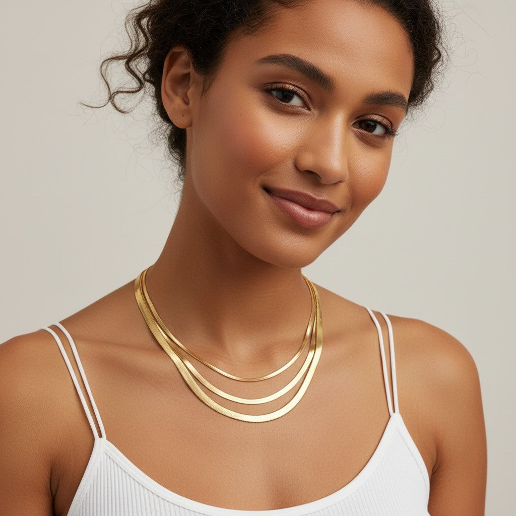 Seraphina Treasures Iridelle layered gold snake chain necklaces on a woman's neck.