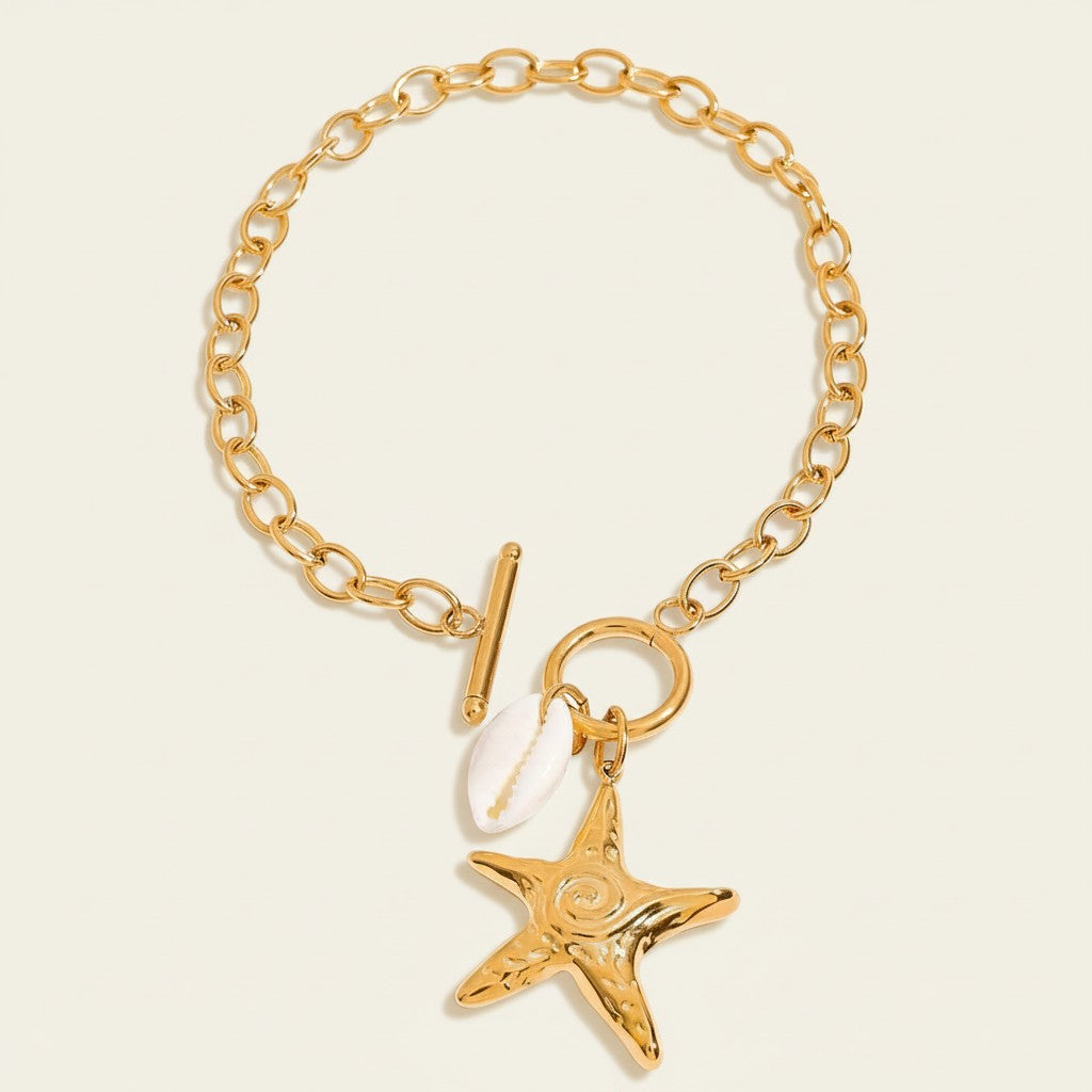 Seraphina Treasures gold chain bracelet with toggle clasp, featuring a starfish charm and a small shell charm. Coastal-inspired jewelry.
