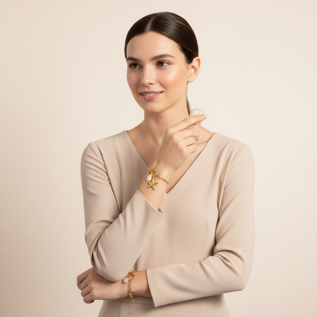 Seraphina Treasures gold-tone bracelet with toggle clasp, featuring a starfish charm and a cowrie shell charm.