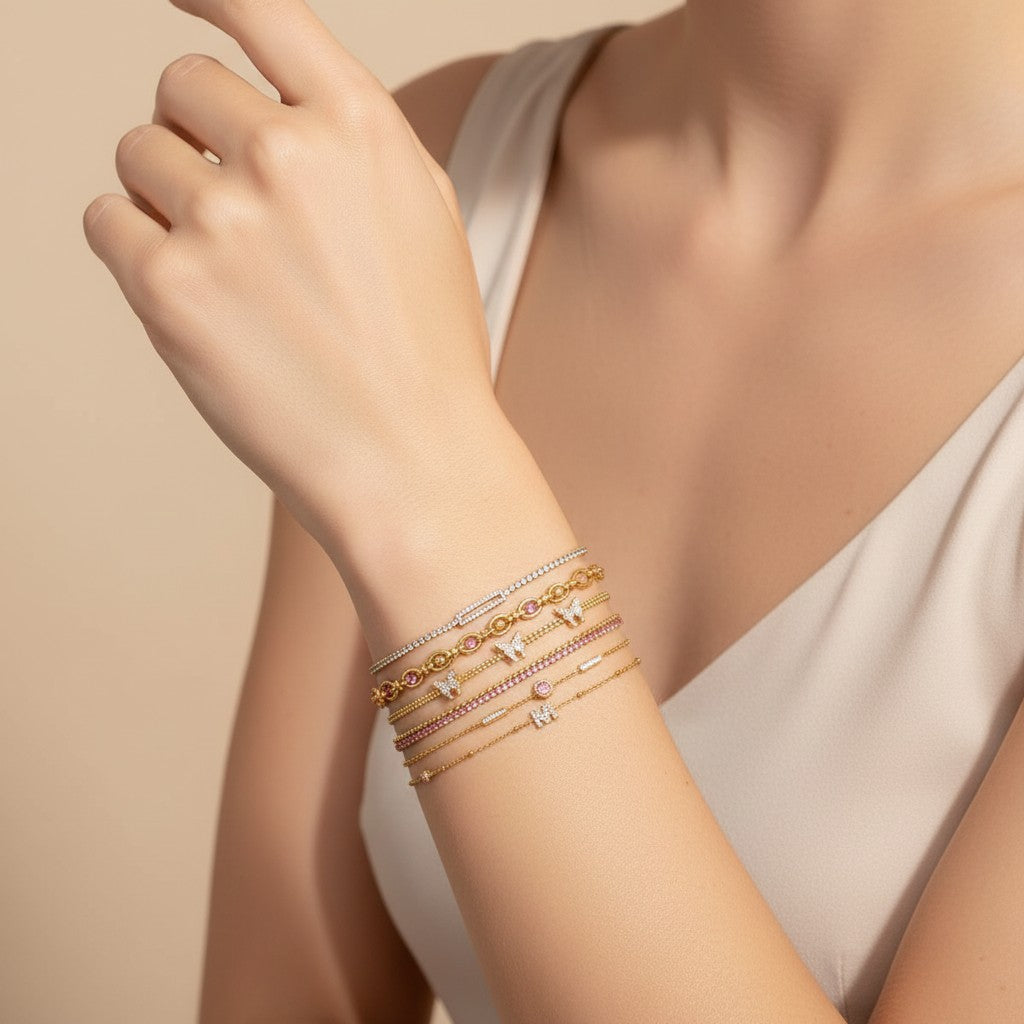 Seraphina Treasures Hestia bracelets: gold chains with cubic zirconia and pink stones, featuring butterfly and rectangular charms.