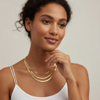 Seraphina Treasures Iridelle layered gold herringbone necklaces on a woman wearing a white tank top.