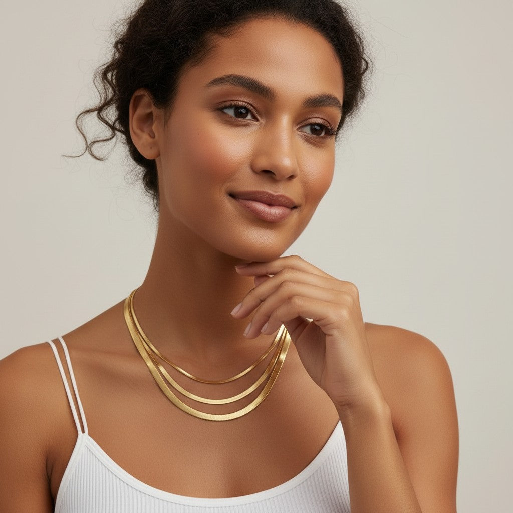 Seraphina Treasures Iridelle layered gold herringbone necklaces on a woman wearing a white tank top.