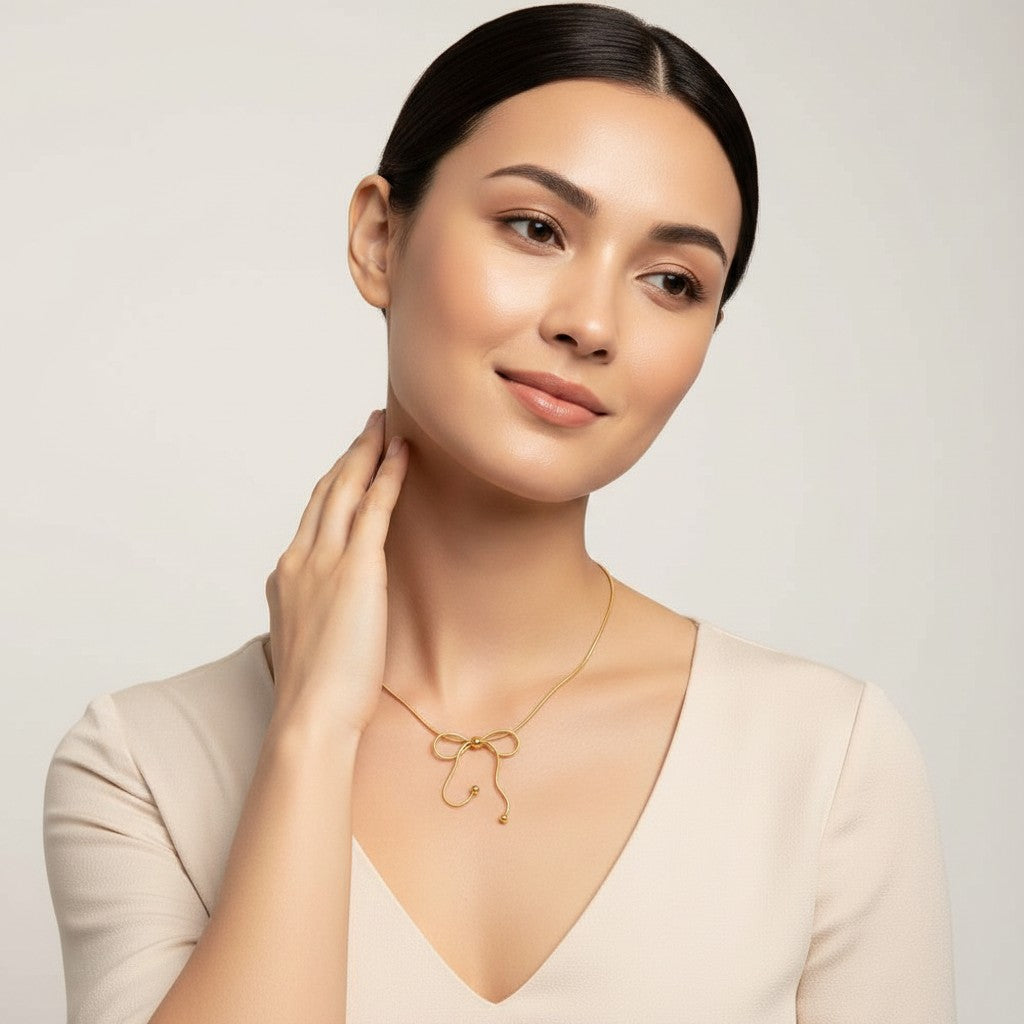 Seraphina Treasures Isara gold bow necklace with delicate chain and bead accents, worn by a woman.