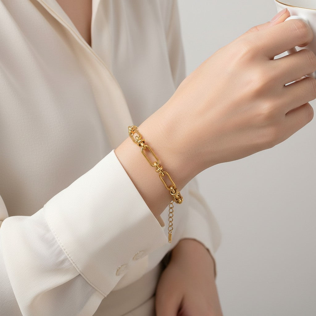 Seraphina Treasures Isolde gold-tone stainless steel link bracelet with knot details and cross clasp.