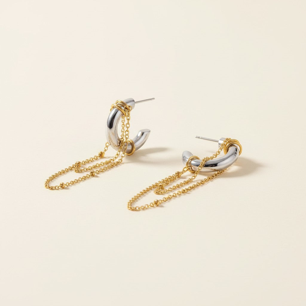 Seraphina Treasures Isonyx sculptural silver C-shaped earrings with dangling gold chains and bead accents.