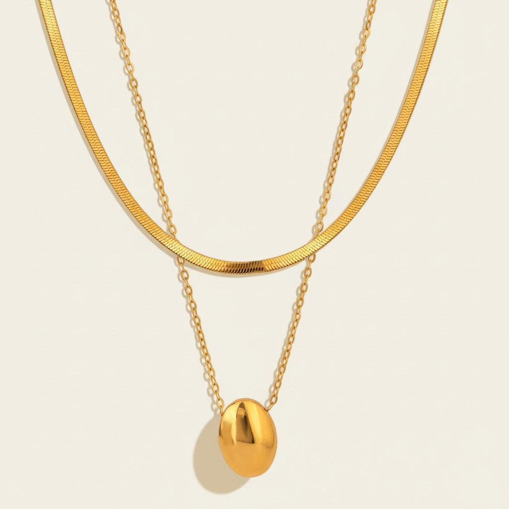 Seraphina Treasures Adelpha layered gold necklace with oval pendant and herringbone chain.