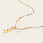 Seraphina Treasures gold necklace with "MAMA" letters and a single pearl accent. Delicate chain with small beads.