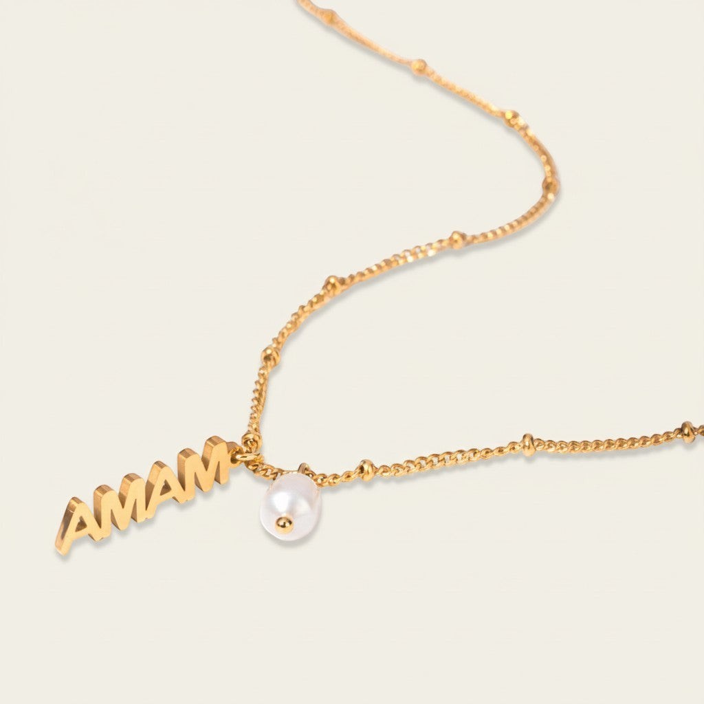 Seraphina Treasures gold necklace with "MAMA" letters and a single pearl accent. Delicate chain with small beads.