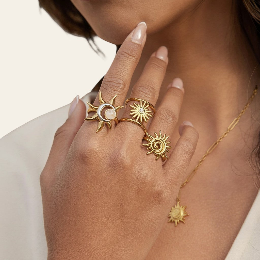 Seraphina Treasures Moirai gold rings with sun and moon motifs, one featuring a pink stone. Celestial-inspired.