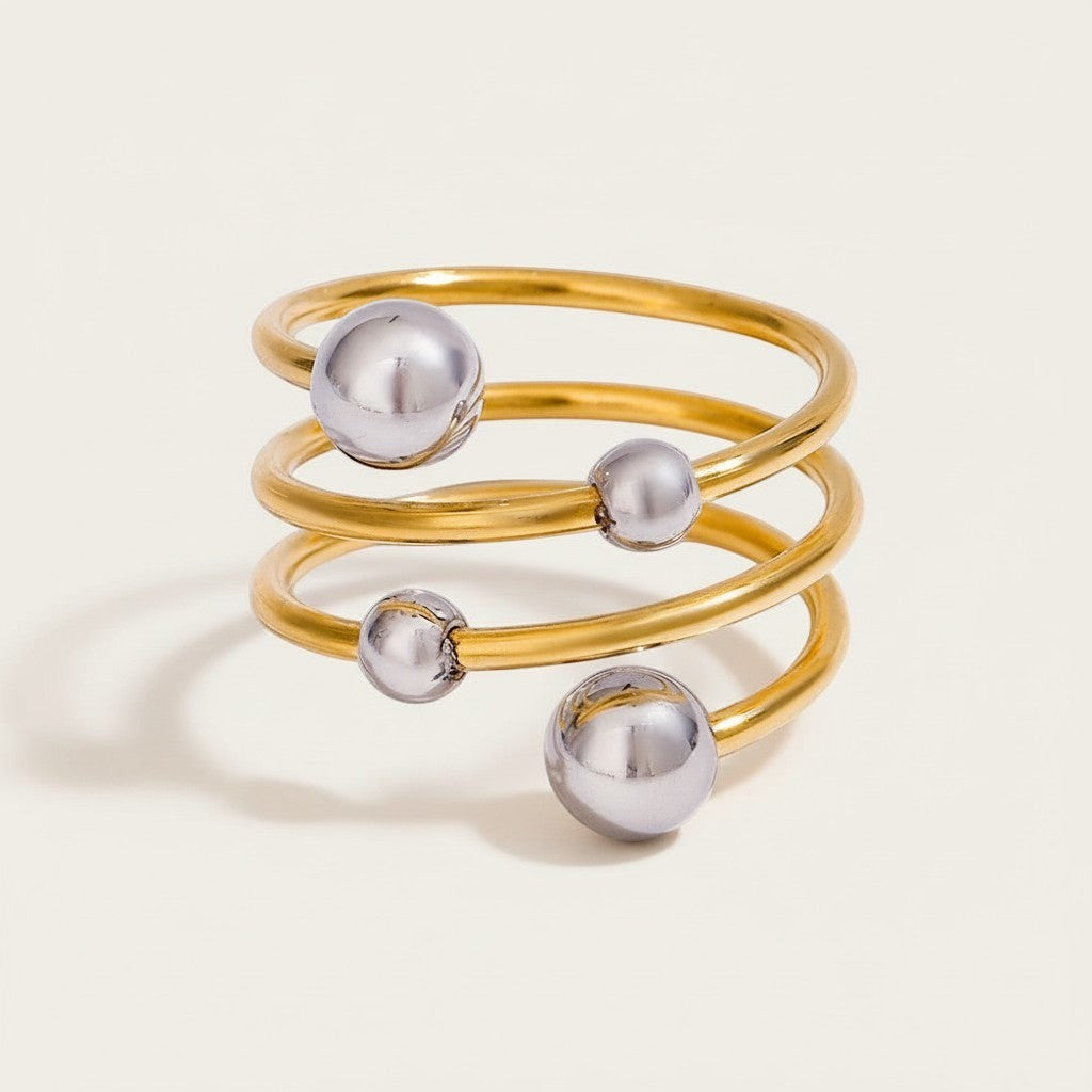 Seraphina Treasures Selenis ring with layered gold-tone spiral and silver beads. Modern mixed metal design.