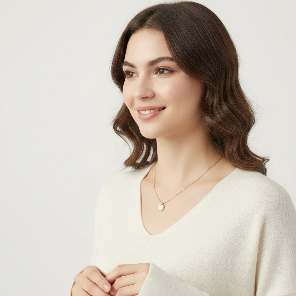 Seraphina Treasures Squerra necklace with a square shell pendant on a gold chain, worn by a woman.