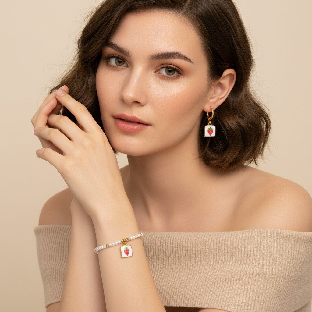 Seraphina Treasures Clytia bracelet and earring set with white pearls, gold accents, and square pendants featuring red strawberries.